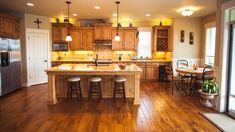 a large kitchen with wooden floors and lots of counter space, including an island in the middle