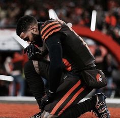 a football player kneeling down on the field with his hands in his pockets and holding his face