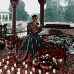 a woman sitting on top of a bed in a room filled with candles and flowers