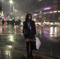 a woman is standing in the rain with an umbrella