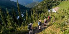 several people hiking up a hill in the mountains