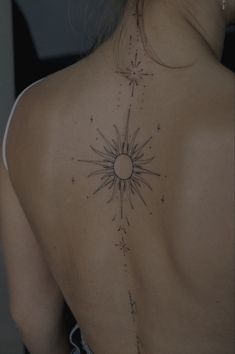 the back of a woman's shoulder with an intricate sun tattoo