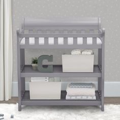 a baby crib with two white baskets on the bottom shelf, and a letter g next to it