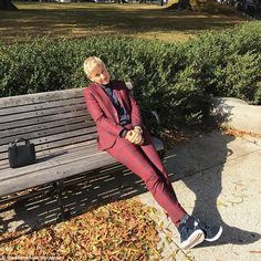 a man in a red suit is sitting on a bench and looking at the camera