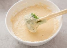 a white bowl filled with broccoli and cream sauce on top of a table