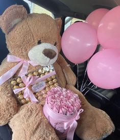 a large teddy bear sitting in the back seat of a car with balloons and pink roses