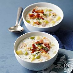 two bowls of soup with bacon, celery and cheese on a blue table