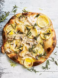 a pizza topped with lemon slices and herbs