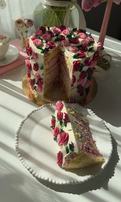 a piece of cake with pink flowers on it sitting on a plate next to a vase