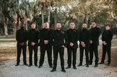 a group of men standing next to each other wearing black suits and red bow ties