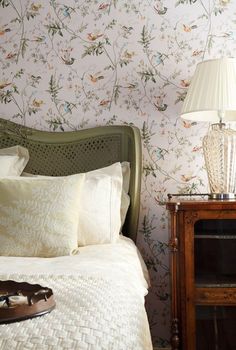 a bedroom with floral wallpaper and white bedding, two shoes on the nightstand