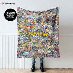 a person standing in front of a wall holding a blanket with pokemon pictures on it