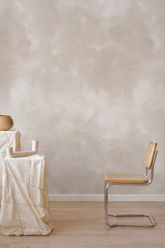 two chairs and a table in front of a wall with clouds painted on the walls