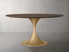 an oval dining table with a gold base and wood top, against a gray background