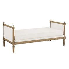 an antique daybed with white linens and wood trim on the legs, against a white background