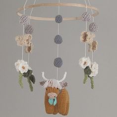 a crocheted deer mobile with flowers hanging from it