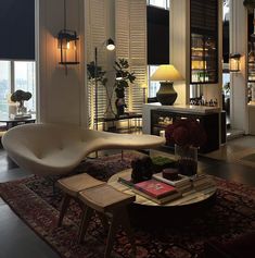 a living room filled with furniture next to a window covered in shutters and windows