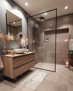 a bathroom with a sink, mirror and shower stall in the middle of it is lit by candles