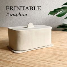 a white box sitting on top of a wooden table next to a potted plant