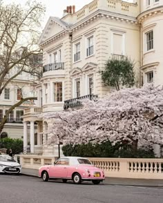 a pink car is parked on the side of the road in front of some white buildings