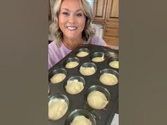 a woman holding a tray full of cupcakes