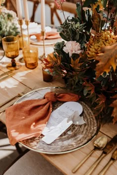 the table is set with place settings, napkins and gold utensil holders