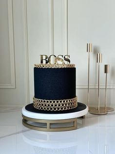 a black and gold wedding cake with the word boss on top sits on a stand