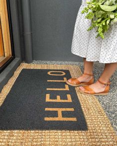 a woman standing in front of a door with her feet on the entrance mat that says hello