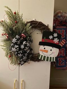 a wreath and snowman decoration hanging on a door