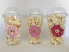 three plastic cups with donuts and sprinkles on the lids are shown