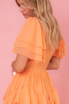 The Solana Dress in Apricot is a stunning piece that will elevate any wardrobe. Its unique features, including a square neckline, flutter sleeves, & a ruffle tiered skirt with pockets, make it both fashionable and functional. The hidden back zipper and functional front corset add a touch of elegance. With a non-stretch fabric and a lined bodice and skirt, this dress offers both comfort and style. Party Square Neck Maxi Dress With Ruffles, Flowy Midi Dress With Ruffle Hem And Sleeve, Orange Maxi Dress With Ruffles And Short Sleeves, Spring Tiered Flutter Sleeve Dress With Ruffle Hem, Flowy Ruffle Dress With Short Sleeves, Spring Tiered Dress With Ruffle Hem And Flutter Sleeves, Brunch Flutter Sleeve Tiered Dress With Ruffle Hem, Flowy Mini Length Tiered Ruffle Dress, Square Neck Ruffle Dress For Brunch