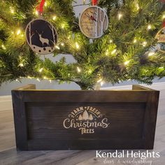 a christmas tree with ornaments hanging from it's branches in front of a wooden box