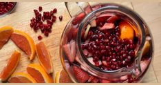 a jar filled with fruit sitting next to sliced oranges and pomegranate