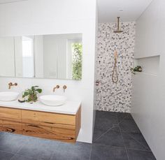 a bathroom with two sinks, mirrors and a shower head mounted to the side of the wall