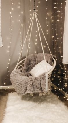 a hanging chair with some lights on the wall behind it and a rug in front of it