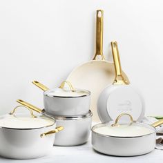 white pots and pans with gold handles on a table