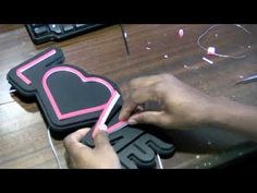 someone is cutting out some paper hearts on top of a wooden table with other items