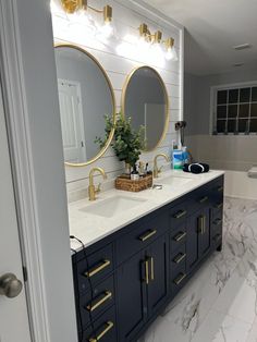 a bathroom with marble counter tops and two round mirrors