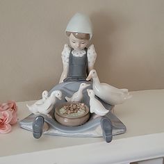 a figurine sitting on top of a white table next to flowers and a bowl