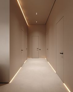 an empty hallway with white walls and lights on either side, leading to two doors