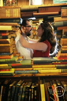 a man and woman embracing each other in front of a book shelf full of books