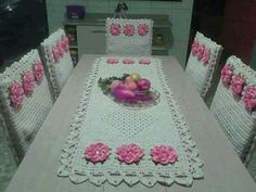 a crocheted table cloth with pink flowers on it and fruit in the center