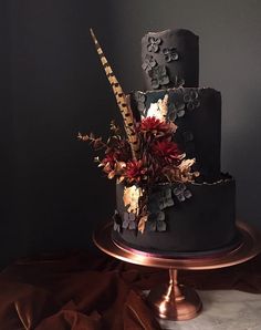 a three tiered cake decorated with flowers and feathers