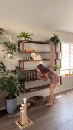 a woman standing in front of a shelf filled with plants