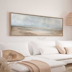 a living room with white furniture and a large painting on the wall over the couch