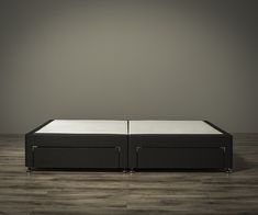 two black and white beds sitting on top of each other in front of a gray wall