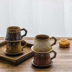 three coffee mugs sitting on top of a wooden tray next to eachother