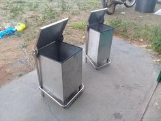 two metal trash cans sitting next to each other on the side of a road in front of a motorcycle