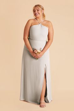 a woman in a grey dress is smiling and posing for the camera with her hands on her hips