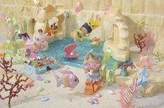 an assortment of toys in the sand with water and sea creatures around them on display